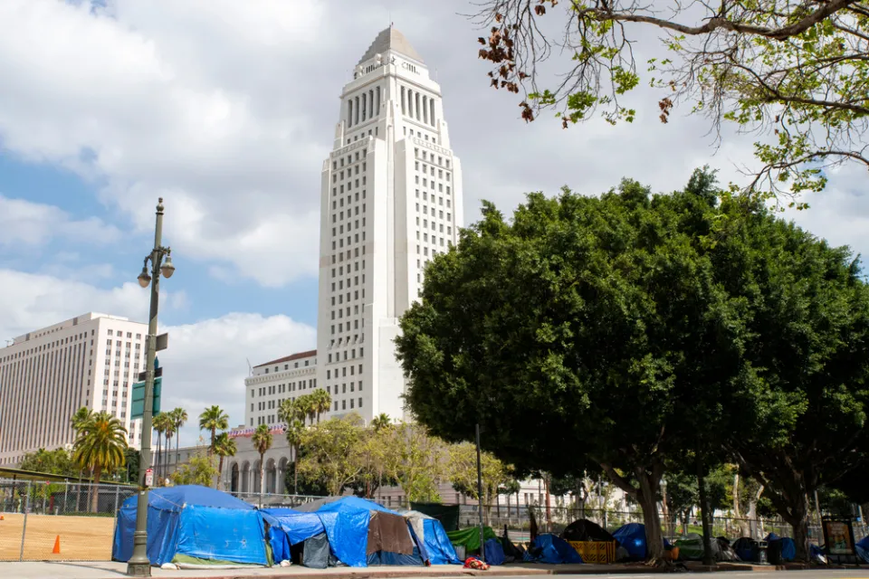 A group of tents line a street in front of Los Angeles City Hall.